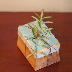 May include: A stack of blue and white paper cards with the text "moonsugars" tied with twine and a sprig of rosemary.