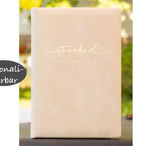 Könnte beinhalten: Ein hellrosa ledergebundenes Tagebuch mit dem Wort "Stammbuch" in goldenen Lettern. Das Tagebuch ist personalisiert mit dem Text "Der Familie".