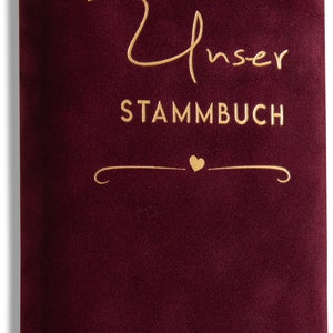 May include: Burgundy velvet book with gold lettering that reads "Unser Stammbuch" with a small heart and the names "Melanie & Niklas Schabert".