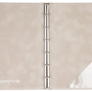 May include: A beige leather binder with a clear plastic pocket on the right side. The binder has a silver ring mechanism and the text "Ringmechanik" is printed on the front cover.