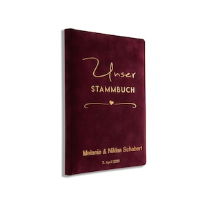 Könnte beinhalten: Burgunderfarbenes Samtbuch mit goldener Aufschrift "Unser Stammbuch" mit einem kleinen Herzsymbol und dem Text "Melanie & Niklas Schabert 11. April 2020".