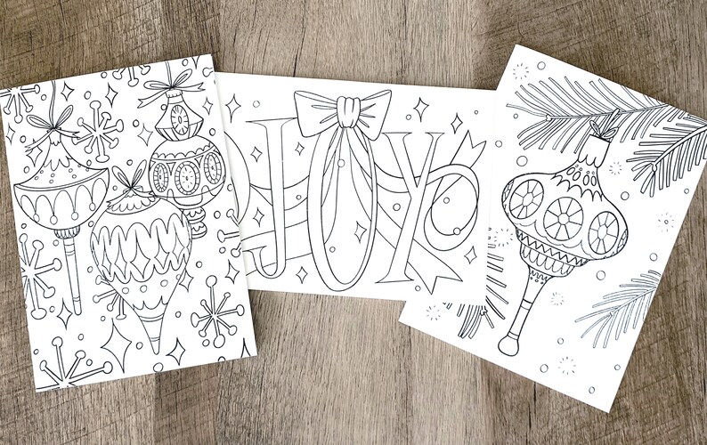 May include: Three black and white coloring pages featuring Christmas ornaments and the word "JOY" with a bow.