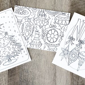May include: Three black and white printable coloring pages featuring Christmas themes. The first page shows a Christmas tree with ornaments. The second page shows a pattern of Christmas ornaments. The third page shows the word "NOEL" with ornaments.
