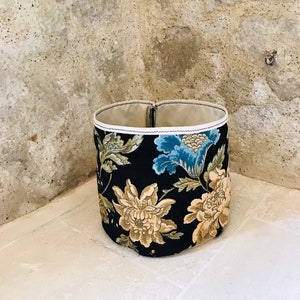 Può includere: Un cesto di stoffa nero per la conservazione con un bordo bianco e un motivo floreale in tonalità di blu, giallo e verde.