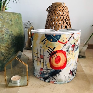 May include: A white fabric storage bin with a black and red abstract design. The bin has a white trim around the top.