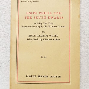 May include: A vintage play script cover for "Snow White and the Seven Dwarfs", a fairy tale play based on the story by the Brothers Grimm. The script is by Jesse Braham White with music by Edmond Rickett. The cover is printed on yellowed paper with red and black text.