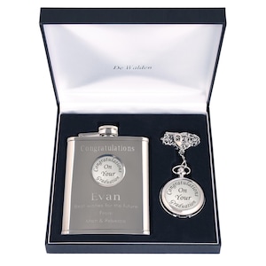May include: A silver hip flask and pocket watch set in a black gift box. The flask and watch are engraved with the text "Congratulations on your graduation." The flask also has the name "Evan" and the message "Best wishes for the future from Matt & Rebecca".