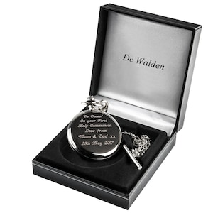 May include: A silver pocket watch with a black chain in a black velvet box. The watch is engraved with the text "To Daniel On your First Holy Communion Love from Mum & Dad xx 28th May 2017". The box is labeled "De Walden".