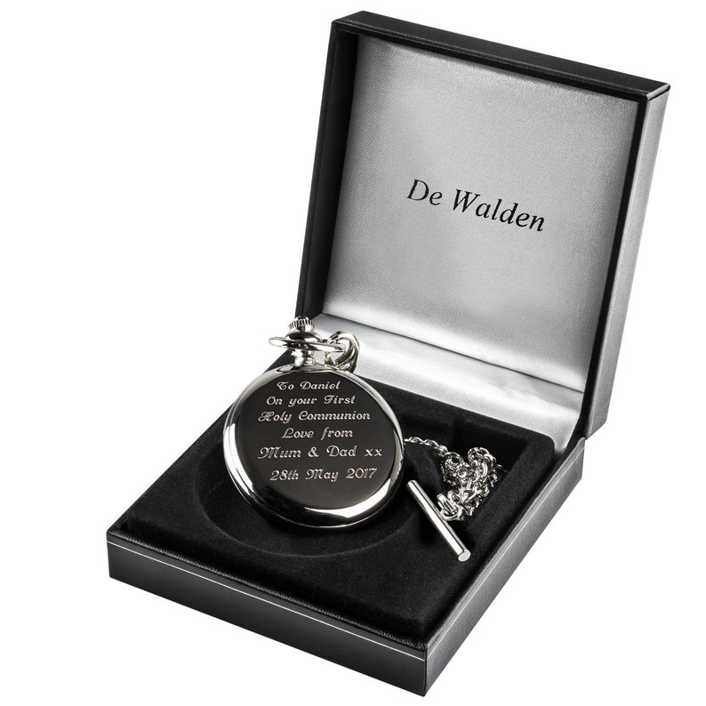 May include: A silver pocket watch with a black chain in a black velvet box. The watch is engraved with the text "To Daniel On your First Holy Communion Love from Mum & Dad xx 28th May 2017". The box is labeled "De Walden".