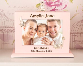 May include: A pink photo frame with the name "Amelia Jane" engraved at the top. The frame holds a family photo and is decorated with silver animal figurines. The text "Christened 29th November 2025" is printed at the bottom.