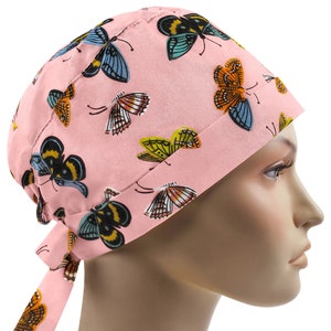 May include: Pink surgical scrub hat with a butterfly print. The hat has a tie at the back.