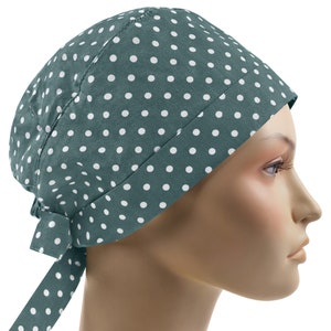 Può includere: Un copricapo color verde acqua con un motivo a pois bianchi. Il copricapo è legato sul retro con lunghi lacci. Il copricapo è mostrato su una testa di manichino.