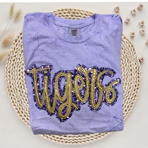 May include: Purple t-shirt with a gold sequined "Tigers" design.
