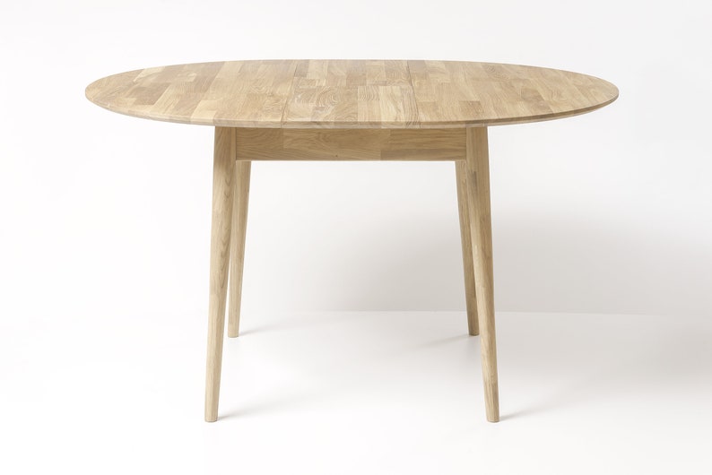 May include: A light wood oval table with a simple design. The table has four legs and a smooth, natural finish.