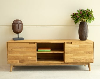 Könnte beinhalten: Ein helles Holz-Entertainment-Center mit zwei Türen und einem Regal. Die Türen sind geschlossen und das Regal ist leer. Das Entertainment-Center steht auf einem hellen Holzboden.