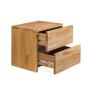 May include: A wooden nightstand with two drawers, both of which are open. The nightstand is made of light brown wood and has a simple, modern design.