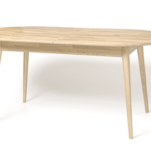 Pu&ograve; includere: Un tavolo da pranzo ovale in legno chiaro con un'estensione a foglia. Il tavolo ha quattro gambe affusolate.