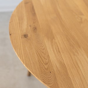 May include: Close-up of a round wooden table top with a natural wood grain finish.