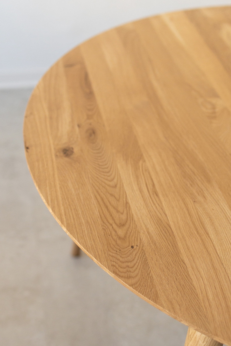 May include: Close-up of a round wooden table top with a natural wood grain finish.