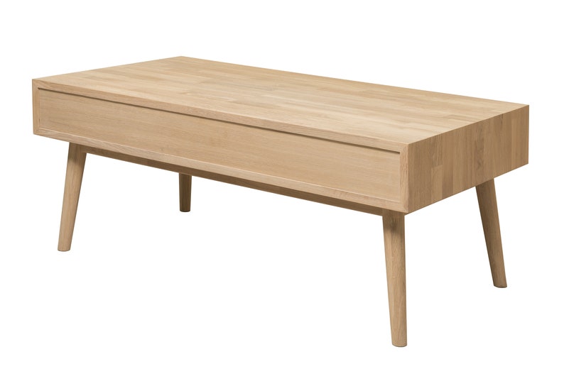 Puede incluir: Una mesa de centro de madera clara con un caj&oacute;n y patas c&oacute;nicas. La mesa est&aacute; hecha de madera maciza y tiene un acabado natural.
