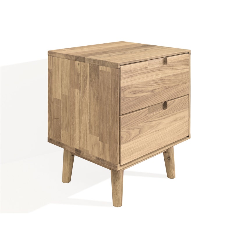 May include: A light oak nightstand with two drawers and a rectangular shape. The nightstand has a natural wood grain finish and is supported by four tapered legs. The drawers have small, rectangular cut-out handles.