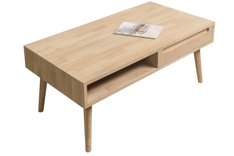 Puede incluir: Una mesa de centro de madera clara con un caj&oacute;n y un estante. La mesa tiene cuatro patas y una tapa rectangular.
