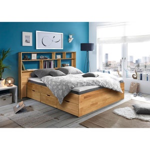 Puede incluir: Cama de madera con cabecero que incorpora estanterías. La cama tiene un marco de madera clara, un colchón gris y un edredón estampado. La cama también tiene cajones de almacenamiento. El fondo es una pared azul con obras de arte y una ventana grande.