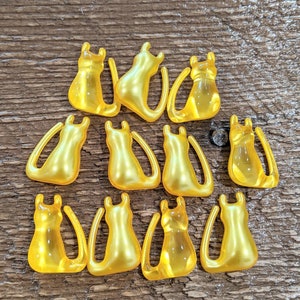 K&ouml;nnte beinhalten: Eine Sammlung von 12 gelben Katzenfiguren aus Kunststoff. Die Katzen sind alle in die gleiche Richtung ausgerichtet und haben eine gl&auml;nzende Oberfl&auml;che.