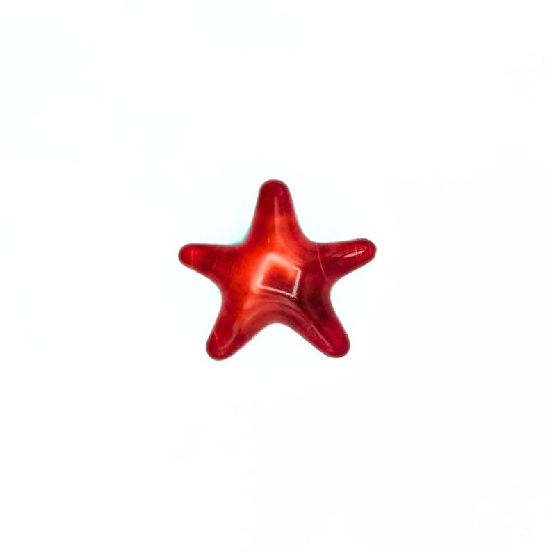 May include: A glossy, red starfish-shaped decorative object. The starfish has five rounded points and a lighter, square-shaped design in the centre. The object is set against a plain white background.
