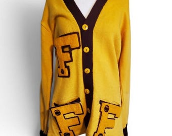 Cárdigan deportivo de estilo retro vintage de los años 50 y 60, color amarillo dorado, con temática de fútbol y academia.