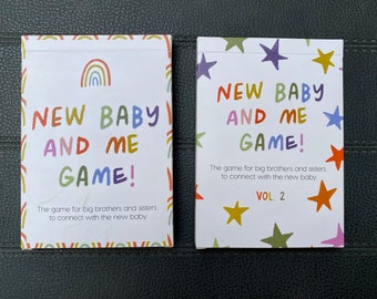 May include: Two colorful card game boxes with the title "New Baby and Me Game!" and the text "The game for big brothers and sisters to connect with the new baby." One box has a rainbow design and the other has a star design. The second box also has the text "Vol. 2".