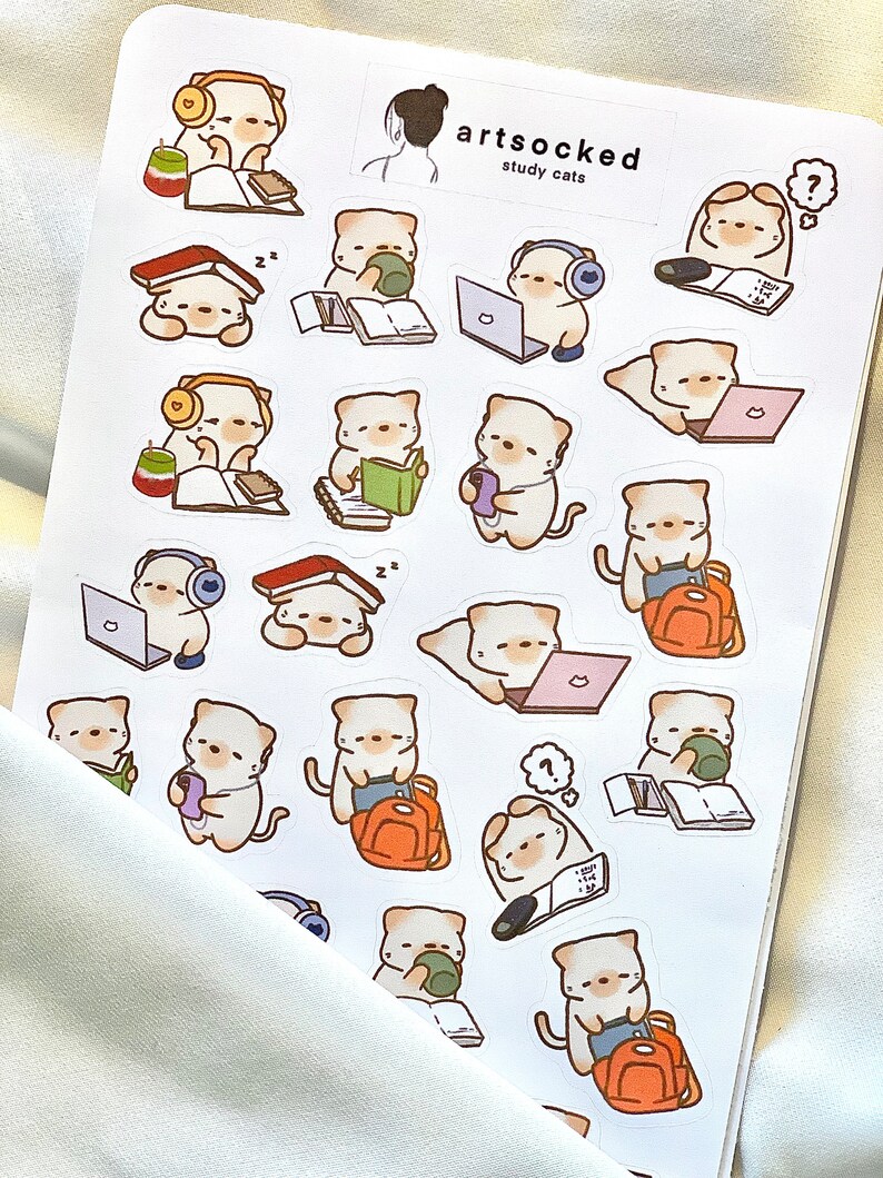 May include: A sticker sheet featuring multiple illustrations of study cats. The cats are depicted with books, laptops, headphones, and backpacks. The sticker sheet has the text "artsocked study cats".