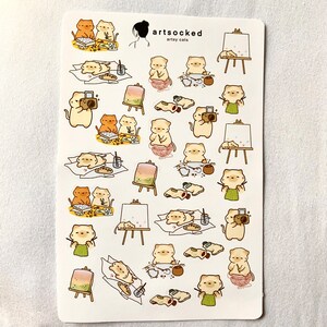 May include: A sticker sheet featuring various illustrations of cats engaged in artistic activities. The cats are depicted painting, taking photos, and relaxing. The sheet includes the text "artsocked" and "artsy cats".