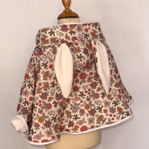 May include: A white ceramic mug with a black handle and the text "But First, Coffee" in a bold, black font. The mug is set against a blurred background, highlighting its clean design.