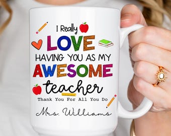 May include: White ceramic mug with the text "I Really LOVE HAVING YOU AS MY AWESOME teacher" in colorful letters. The mug also includes a pencil, apple, and heart graphic, and the name "Mrs. Williams".