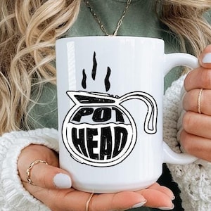 May include: White ceramic mug with a black and white illustration of a coffee pot with steam coming out of it and the text "POT HEAD".