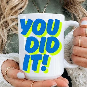 May include: White ceramic mug with a blue and yellow graphic that says "YOU DID IT!"