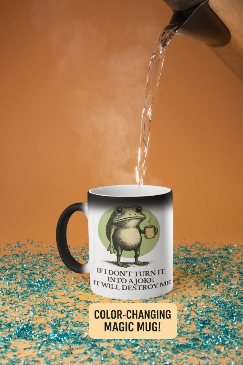 Puede incluir: Una taza m&aacute;gica que cambia de color con asa y borde negros. La taza presenta una rana llorando sosteniendo una taza, con el texto "IF I DON'T TURN IT INTO A JOKE IT WILL DESTROY ME". La taza es blanca y cambia de color.