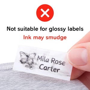 May include: A white label with the name "Mila Rose Carter" and a butterfly graphic, with smudged ink. The text "Not suitable for glossy labels" and "Ink may smudge" is displayed above the label, with a red "X" symbol.