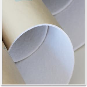 May include: Close-up of three beige cardboard tubes with white edges. The tubes are rolled up and have a blue stamp with the text "ENVELOPPE" on the side.