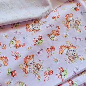 May include: Purple fabric with a repeating pattern of white mushrooms with houses inside. The mushrooms have red tops with white polka dots. There are also small white flowers and green leaves throughout the pattern.