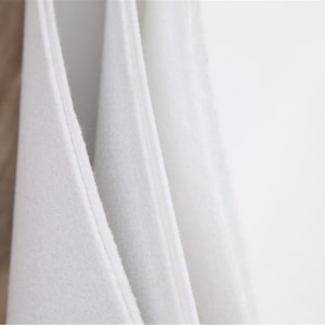 May include: Close-up of three white fabric swatches, showing the texture and weave of the material.