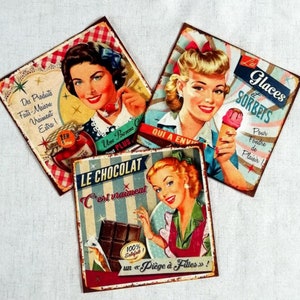 May include: Three vintage-style metal signs with retro illustrations of women. One sign features a woman with a jar, another with an ice cream cone, and the last with chocolate. Each sign has French text and a distressed, aged appearance.