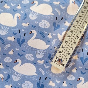 Pu&ograve; includere: Tessuto blu con un motivo di cigni bianchi. I cigni nuotano in uno stagno con ninfee e canne. Il tessuto &egrave; perfetto per il quilting, la cucitura o l'artigianato.