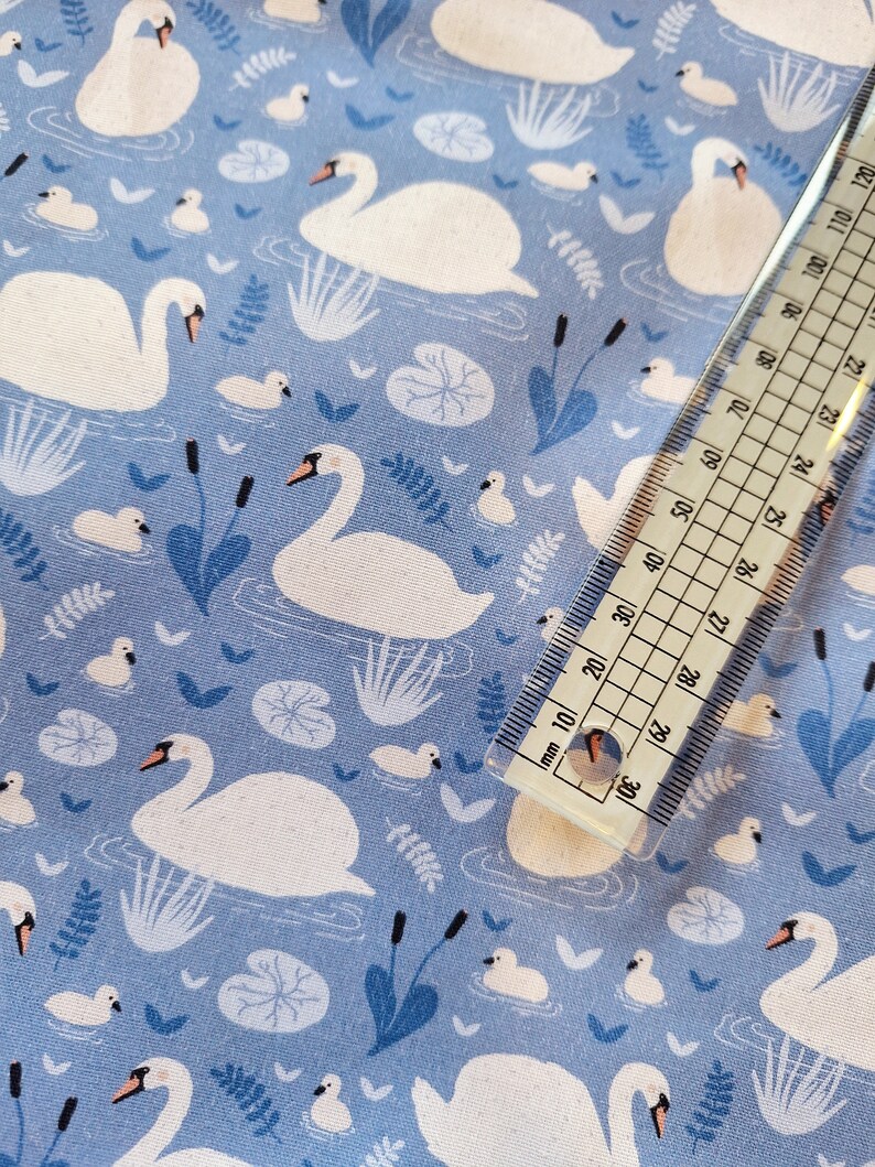 Pu&ograve; includere: Tessuto blu con un motivo di cigni bianchi. I cigni nuotano in uno stagno con ninfee e canne. Il tessuto &egrave; perfetto per il quilting, la cucitura o l'artigianato.