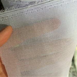 May include: White sheer fabric with a fine mesh weave. The fabric is folded and has a stitched edge.