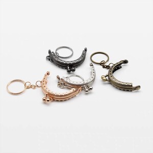 May include: Four different metal purse frames with key rings. The frames are in silver, gold, black, and bronze.