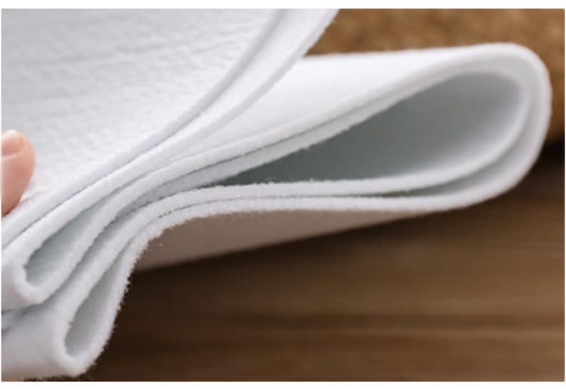 May include: Close-up of a white, folded fabric. The fabric is soft and textured, with a slightly fuzzy surface.