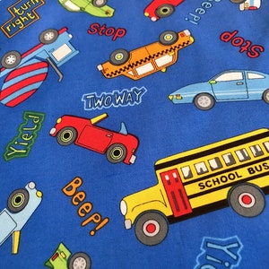 May include: Blue fabric with a repeating pattern of various vehicles, including a school bus, a red convertible, a yellow taxi, a blue car, and a cement truck. The fabric also features words like "Stop", "Yield", "Two Way", "Beep!" and "Turn Right".