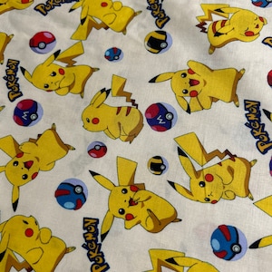 May include: White fabric patterned with yellow Pikachu characters, red and white Pok&eacute; Balls, and blue and black Pok&eacute; Balls. The word "Pokemon" is printed in blue.